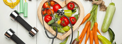 verduras para evitar diabetes en el centro. Tomates, zanahorias, calabacín y pimientos. En la izquierda se ven unas pesas.