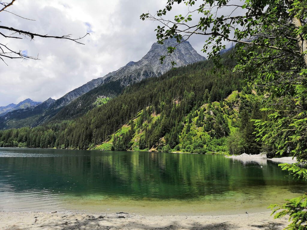 lago verdoso en medio de la montaña en Italia. Se observa un paisaje montañoso de color verde.